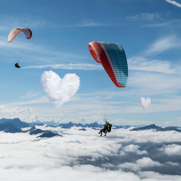 Two tandem paragliders above the clouds on cloud 7. marriage proposal